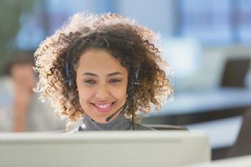 Businesswoman with headset working at computer in office