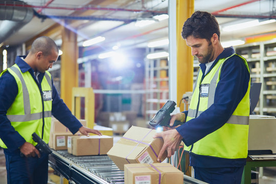 Workers scanning and processing boxes on conveyor belt in distribution warehouse