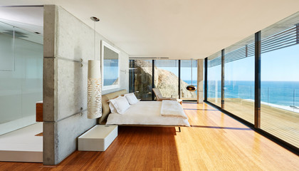 Modern luxury bedroom open to patio with sunny ocean view