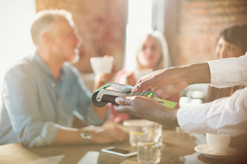 Waiter using credit card reader at restaurant table