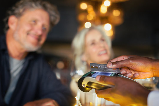 Close up couple paying waiter with credit card reader