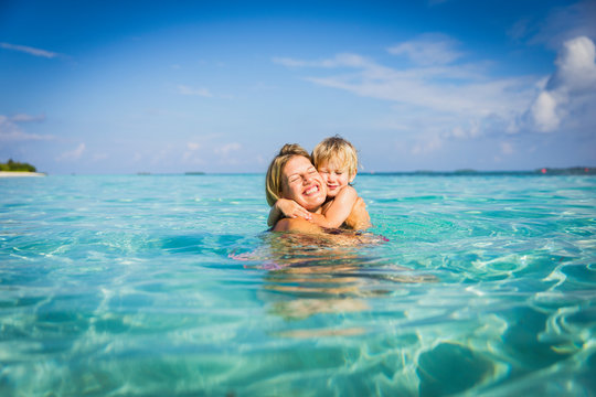 Enthusiastic mother hugging son in tropical ocean