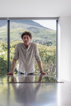 Portrait smiling man leaning on counter in sunny kitchen