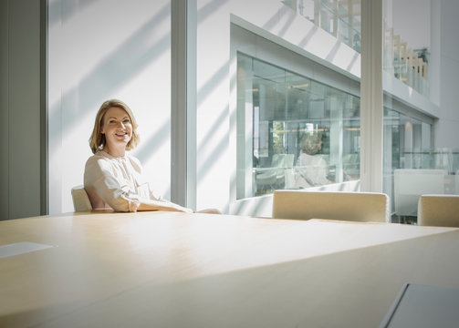 Portrait smiling businesswoman in sunny conference room