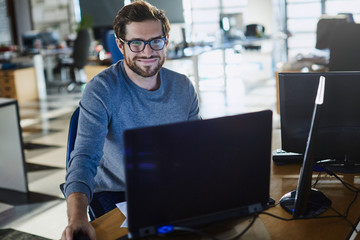 Portrait smiling businessman working at computer in office