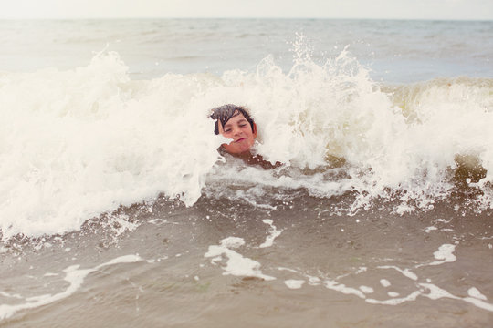Waves splashing around boy swimming in summer ocean
