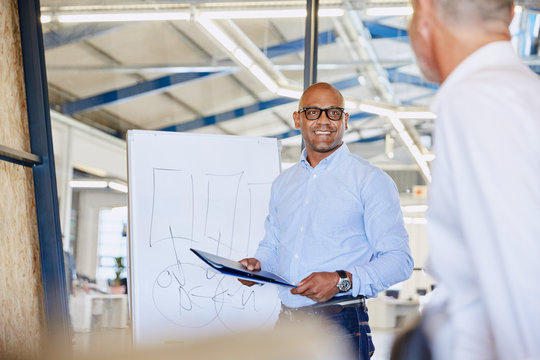 Businessman at flipchart leading meeting in conference room