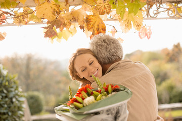 Husband surprising wife with flower bouquet on autumn patio