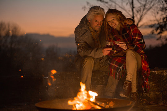 Couple drinking enjoying autumn campfire