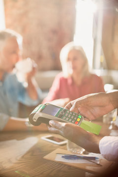 Waiter using credit card reader at restaurant table