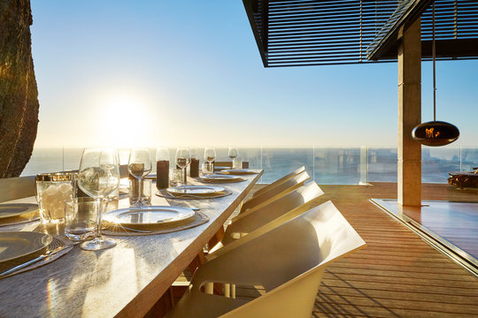 Sun shining over ocean behind luxury patio dining table with placesettings