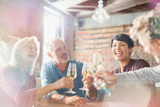 Friends toasting white wine glasses at restaurant table