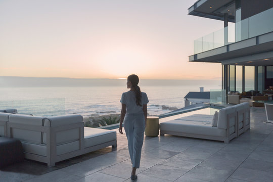 Woman walking on luxury home showcase exterior patio at sunset