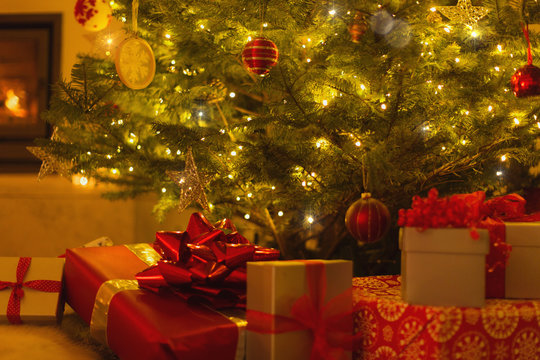 Gifts with red bows under illuminated Christmas tree