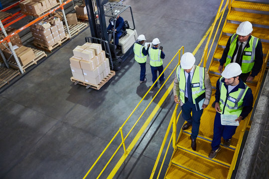 Forklift, managers and workers in distribution warehouse