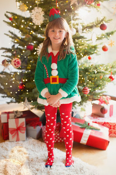 Portrait smiling girl wearing elf costume in front of Christmas tree