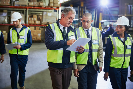 Manger and workers with clipboard talking in distribution warehouse