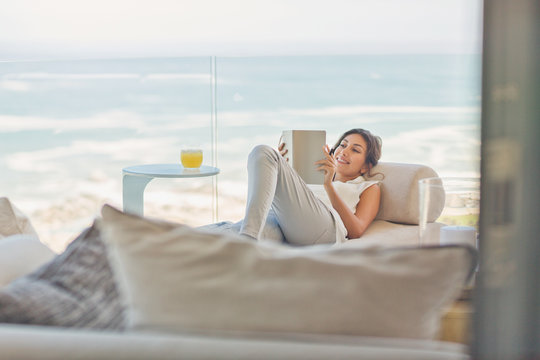 Woman Relaxing Reading Book On Chaise Lounge On Luxury Balcony With Ocean View