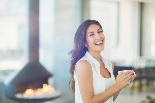 Portrait smiling woman drinking coffee near fireplace