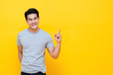 Happy smiling young handnsome Asian man pointing hand up
