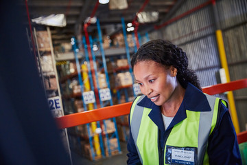 Smiling female worker looking down in distribution warehouse