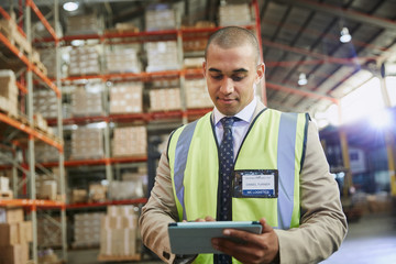 Manager using digital tablet in distribution warehouse