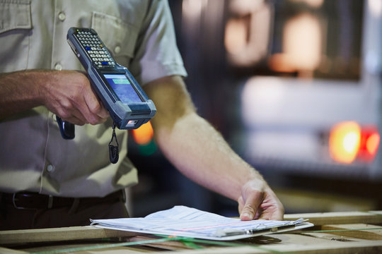 Worker with scanner scanning paperwork in distribution warehouse