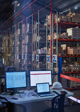 Desk with laptop and computers in distribution warehouse