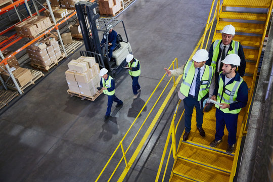 Forklift, managers and workers talking in distribution warehouse