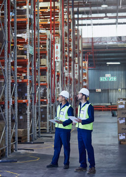 Workers with clipboards looking away in distribution warehouse