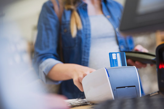 Female shopper using credit card reader in shop