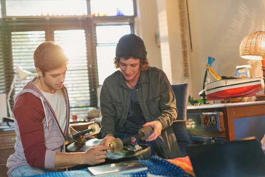 Young male friends examining skateboard