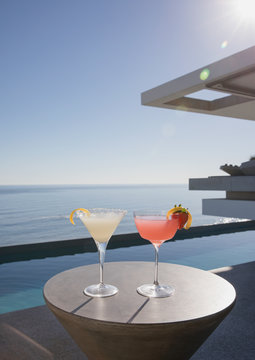 Cocktails in martini glasses on sunny luxury patio with ocean view