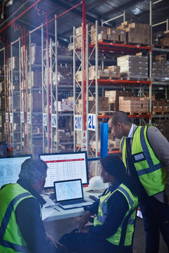 Managers at laptop and computers in distribution warehouse