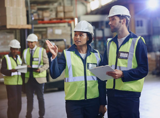 Workers with clipboard talking in distribution warehouse