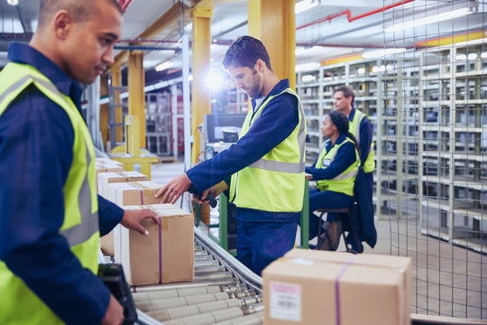 Workers scanning and processing boxes on conveyor belt in distribution warehouse