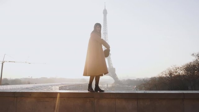 Backlit beautiful happy smiling woman doing fun walk on fence at amazing sunset Eiffel Tower view in Paris slow motion.