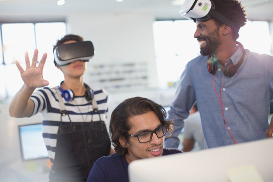 Computer programmers testing virtual reality simulator glasses in office