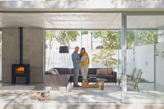 Couple using laptop in modern living room open to patio