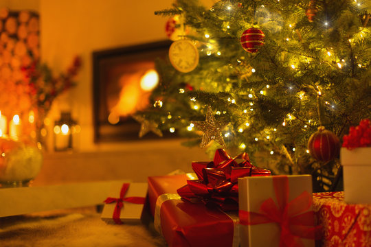 Gifts under Christmas tree in ambient living room with fireplace