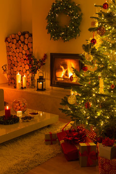 Ambient fireplace and candles illuminating living room with Christmas tree and decorations