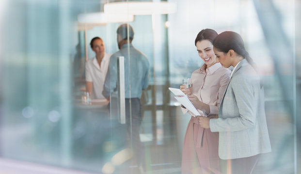 Businesswomen talking, reviewing paperwork in office