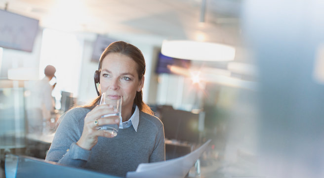 Businesswoman wearing headset drinking water in office
