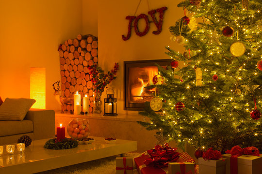 Ambient fireplace and candles in living room with Christmas tree