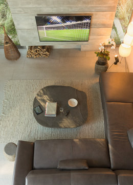 View from above soccer game on TV in modern, luxury home showcase interior living room