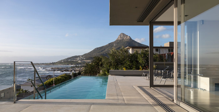 Mountain and ocean view beyond lap swimming pool outside luxury home showcase exterior