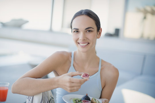 Portrait smiling, confident brunette woman eating figs