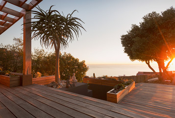 Tranquil modern, luxury home showcase exterior wooden deck with sunset ocean view