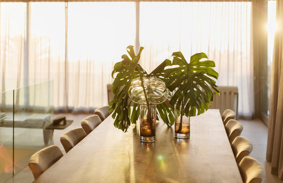 Tropical plant leaves in vases on dining table