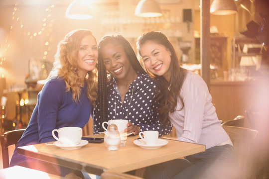 Portrait smiling women friends drinking coffee at cafe table